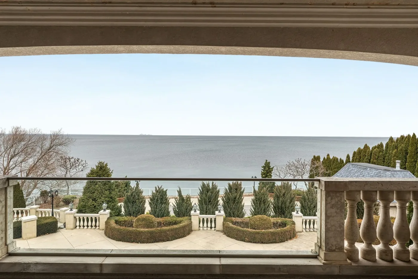 A lake view from a stone terrace over a formal garden